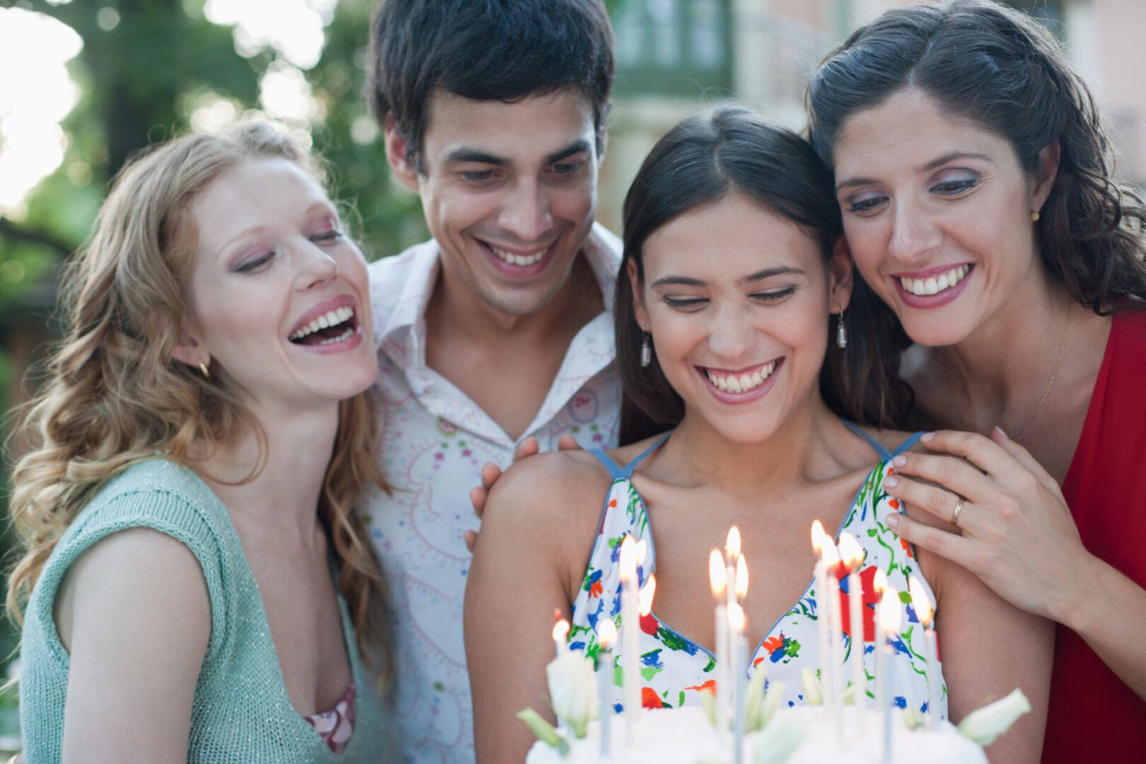 Friends smiling around birthday cake with candles