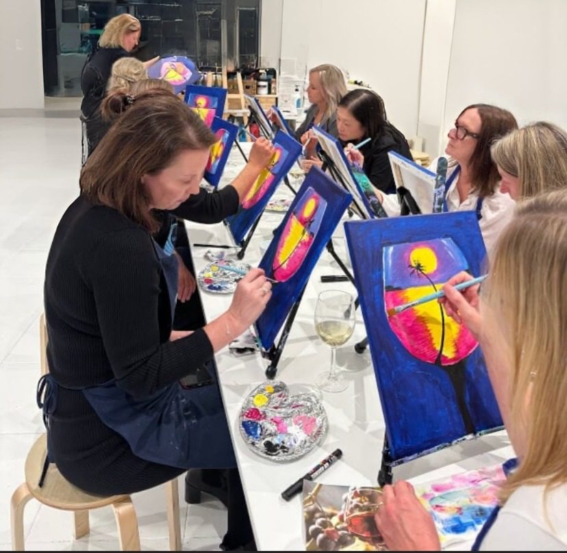Participants painting vibrant sunset canvases in workshop