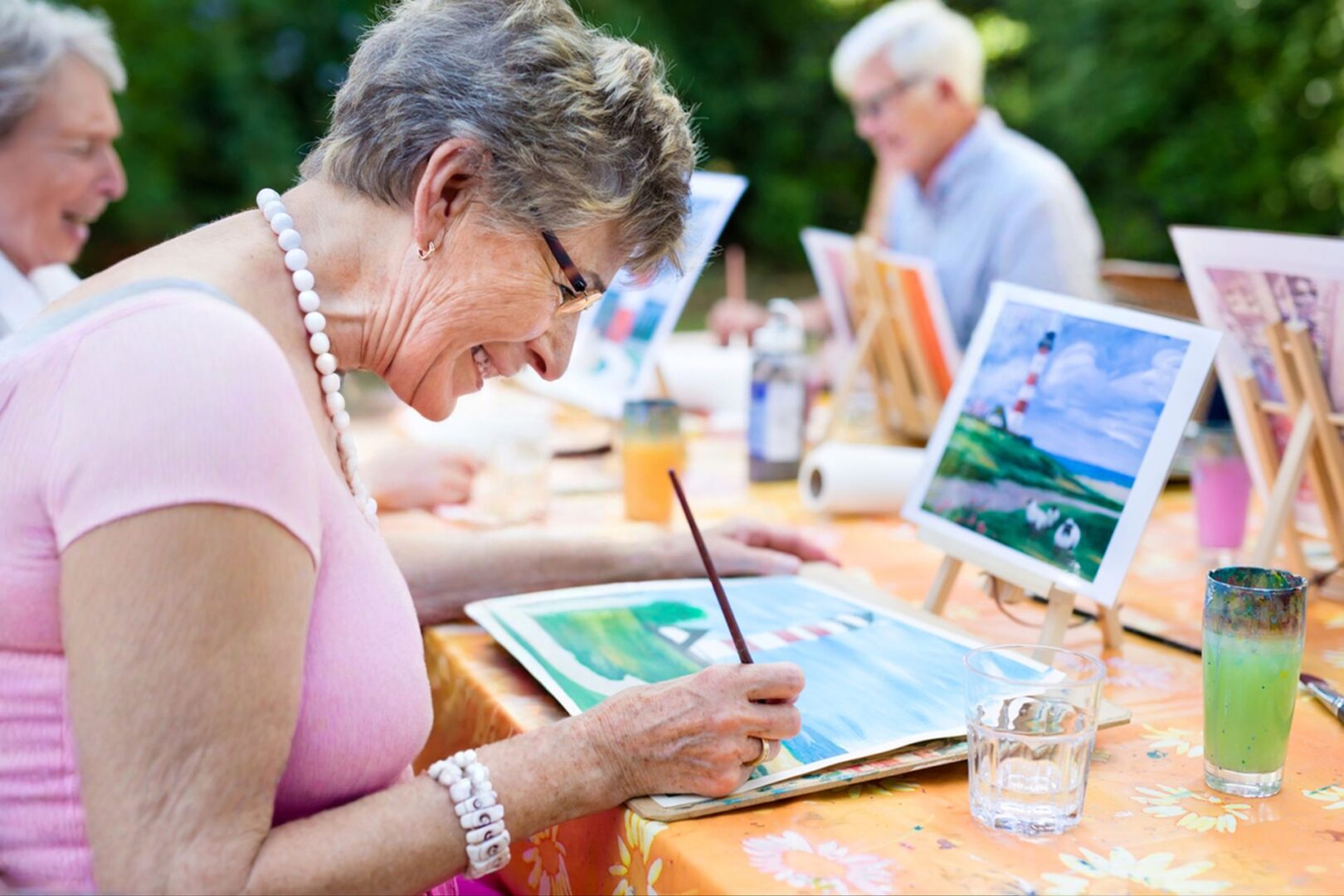 Senior woman painting outdoors with peers