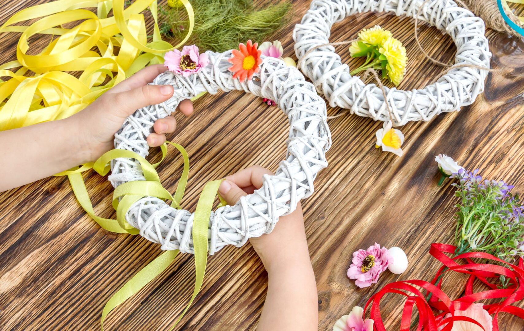 Hands decorating white wicker wreath with ribbon